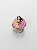 A cupcake decorated with strawberry cream and penguin