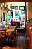Im Landhausstil gestaltete Wohnküche; Wohnzimmerwand mit farbenfrohen Gemälden im Hintergrund