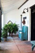 Entrance area of old country house with curved porch and antique bench painted light blue on large stone flags