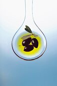 Olive oil and olives on a salad spoon