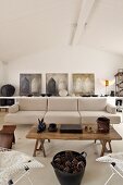 Rustic coffee table in front a designer couch upholstered in light fabric in a modern living room and a row of pictures on the wall