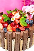 Schokoladentorte mit Schokoriegeln, Waffelröllchen, Sommerfrüchten und Erdbeerblättern