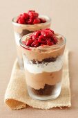 Layered dessert made with brownies, chocolate mousse, cream and raspberry sauce