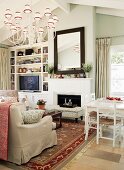 Interior with traditional-style sofa set in front of fireplace & white-painted dining set