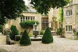 Kegelförmige Büsche um Springbrunnen im Innenhof eines englischen Schlosses