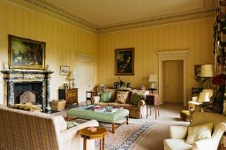 Grand salon with yellow striped walls and simple, country-style sofa set in front of open fireplace