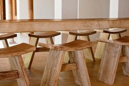 Esstisch aus Massivholz mit dazupassenden, einfachen Holzhockern mit konkaver Sitzfläche