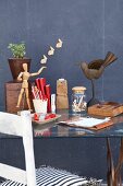 Simple wooden chair at glass table with stationary against dark grey wall