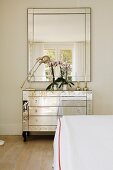 Mirrored chest of drawers and matching mirror in simple bedroom