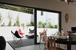 Dining area in front of partially open terrace window showing view of Butterfly chairs in various colours