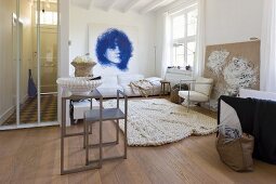 Grosser Wohnraum mit modernem Tisch und Stuhl vor Loungeecke mit hellem Teppich und Portraitzeichnung an Wand