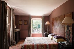 Braunrosa getöntes Schlafzimmer mit auffällig großen Nachttischlampen beidseits des Doppelbetts