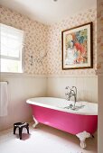Badezimmerecke mit freistehender, pinkfarbener Badewanne; darüber ein modernes Gemälde an tapezierter Wand mit luftigem Federn-Motiv