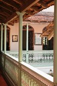 Roofed balcony with pale green and white carved balustrade encircling courtyard