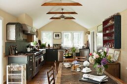 Attic kitchen with country-house-style wooden floor and rustic wooden table combined with dark fitted units