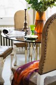 Inviting seating area with Baroque, upholstered wooden chairs and modern glass table