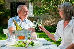 Älteres Paar beim Anstossen mit Weißwein