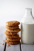 A stack of peanut biscuits next to a bottle of milk