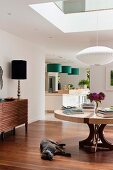 Open-plan interior with Japanese-style pendant lamp, elegant table lamp and green pendant lamps above kitchen counter