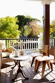 Classic, wooden chairs and traditional side table on wooden floor of colonial-style veranda