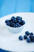 Fresh Blueberries in a Paper Muffin Cup; Blueberries Next to Cup