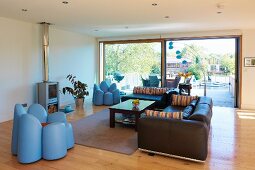 Bright, modern living room with large window, leather sofas and original armchairs shaped like flowers