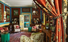 Eine Überfülle an Mustern und Gemälden vor erdfarben getönten Wänden in einem grossen Wohnraum