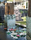 Künstliche Seerosen und Kunstobjekte im Wasserbassin unterhalb eines Wohnhauses