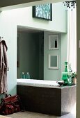 Freistehende, moderne Badewanne teils in Nische eines hellgrün gestrichenen Bades