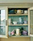 Close up of glass fronted cabinet with assortment of cups and saucers