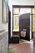 Letterbox above post basket on open front door surrounded by leaded stained glass windows