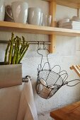 Green asparagus in sink and wire basket of fresh eggs below crockery on shelf