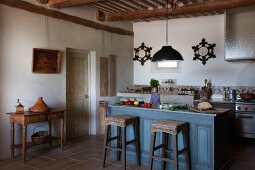 Hocker mit Sitzgeflecht vor blau lasierter Frühstückstheke und Konsolentisch in provenzalischer Küche