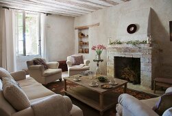 Seating area with upholstered furniture and simple coffee table in front of rustic fireplace; shelving in masonry niche in background