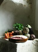 Duck breast, aubergine, artichokes and carrots on plastered sandstone ledge