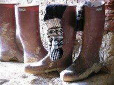 Schmutzige Gummistiefel und Stricksocken auf einer alten Steinterrasse