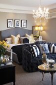 Traditional bedroom with grey double bed and black upholstered sofa at foot; soft scatter cushions create a cosy atmosphere