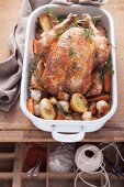 Roast chicken with root vegetables in a roasting dish, seen from above