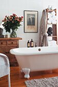 Traditional bathroom with free-standing bathtub, vintage chest of drawers and magnificent bouquet of roses in glass vase
