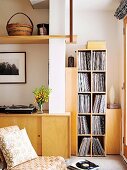 Retro chair in front of fitted sideboard and record collection on modern shelving in corner of living room