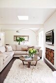 Cream-colored corner couch with a round wooden table on flocked carpet; behind it a chrome arc lamp