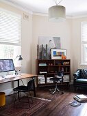 Table and retro chair below window with half-closed louver blinds next to shelving unit in office