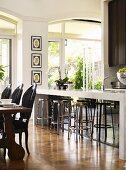 Stools at breakfast bar and rustic dining table with black upholstered chairs