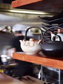 Teapots and black crockery on fine wood shelf