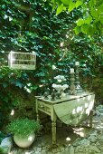 Vintage candlesticks on rustic wooden table against climber-covered facade (Virginia creeper)