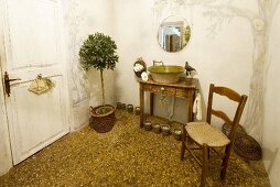 Simple bathroom with vintage washstand and potted tree on terrazzo floor