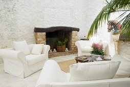 Elegant sofa set with pale upholstery in front of open fireplace on Mediterranean loggia