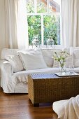 White sofa and wicker table in front of window