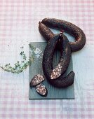 Bavarian black pudding on a chopping board with a sprig of thyme