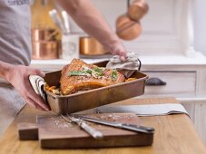 A man holding crispy roast pork in a roasting tin